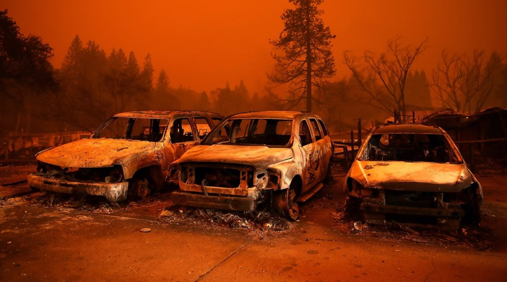 Burned out cars and the orange-smokey sky from an active wildfire