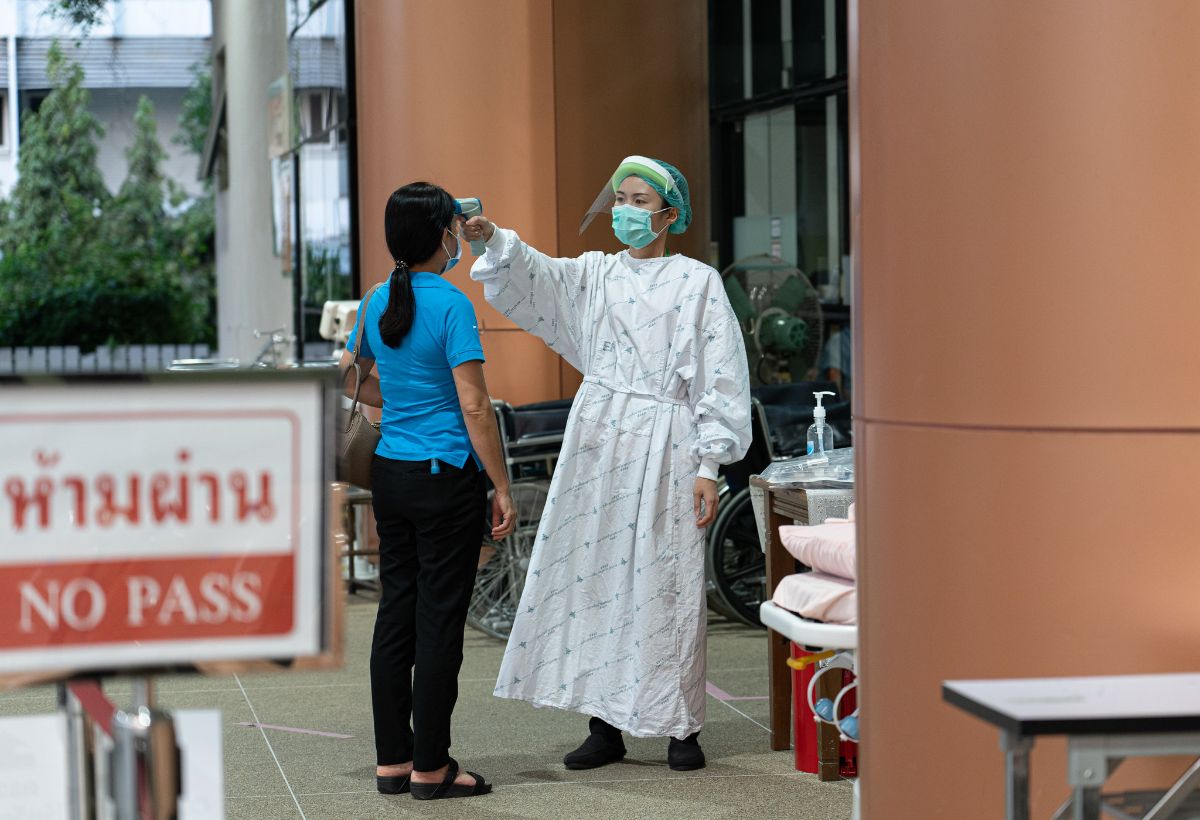 A healthcare worker takes another person's temperature at the Thailand Bamrasnaradura Infectious Disease Institute in April 2020.