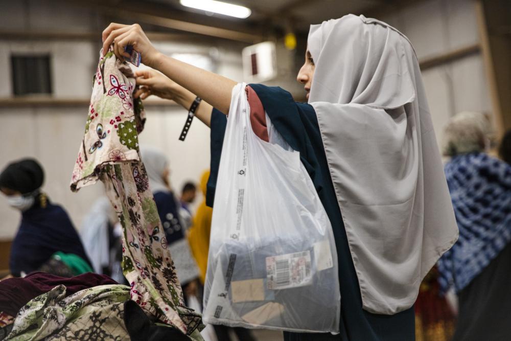 An Afghan evacuee examines a piece of clothing at a donation facility at Fort McCoy in Wisconsin on Sept. 7, 2021, as part of the Operation Allies Welcome effort. (Photo: Spc. Rhianna Ballenger, 55th Signal Company / U.S. Army)