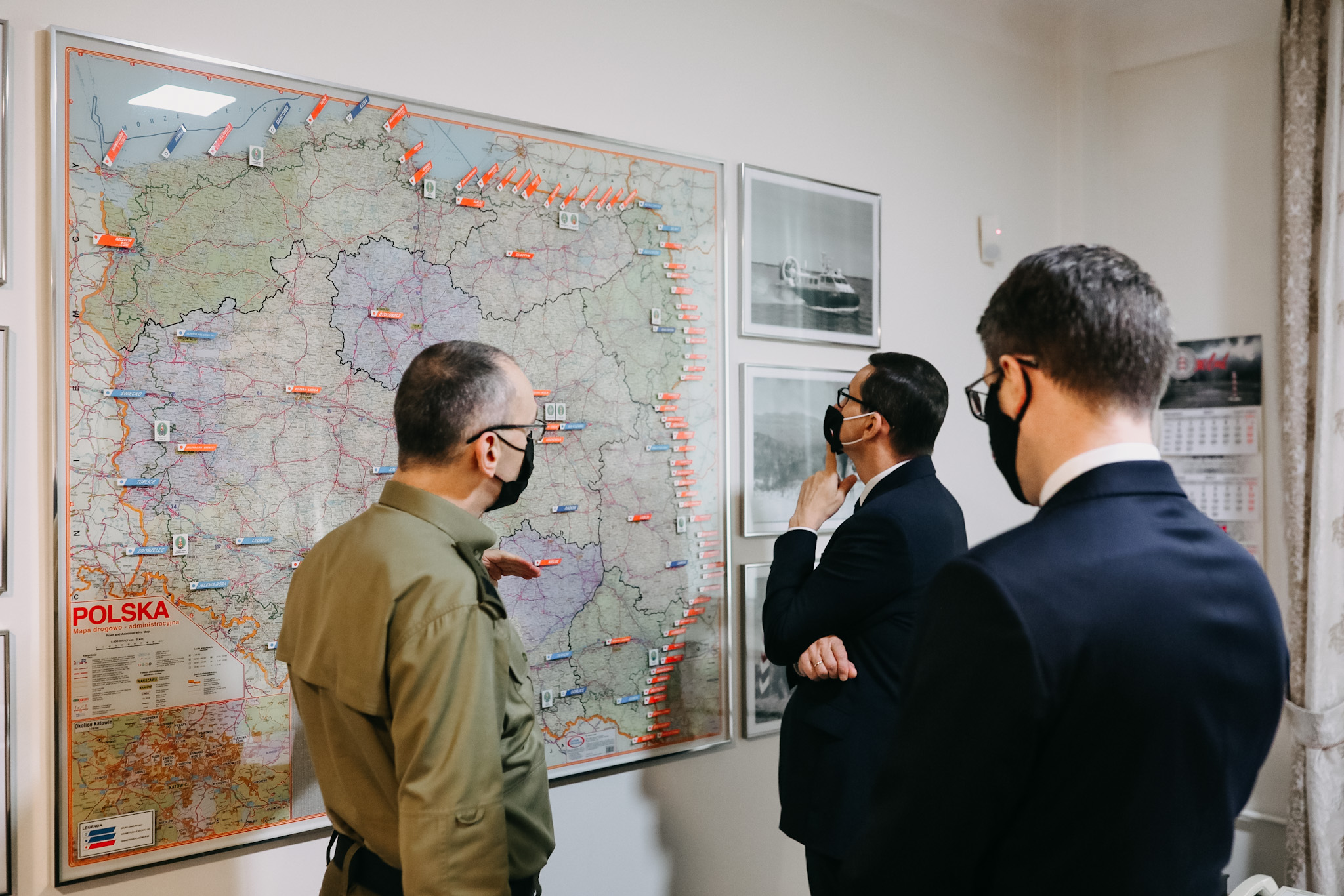 Three individuals look at a map in Poland that shows all border crossings.