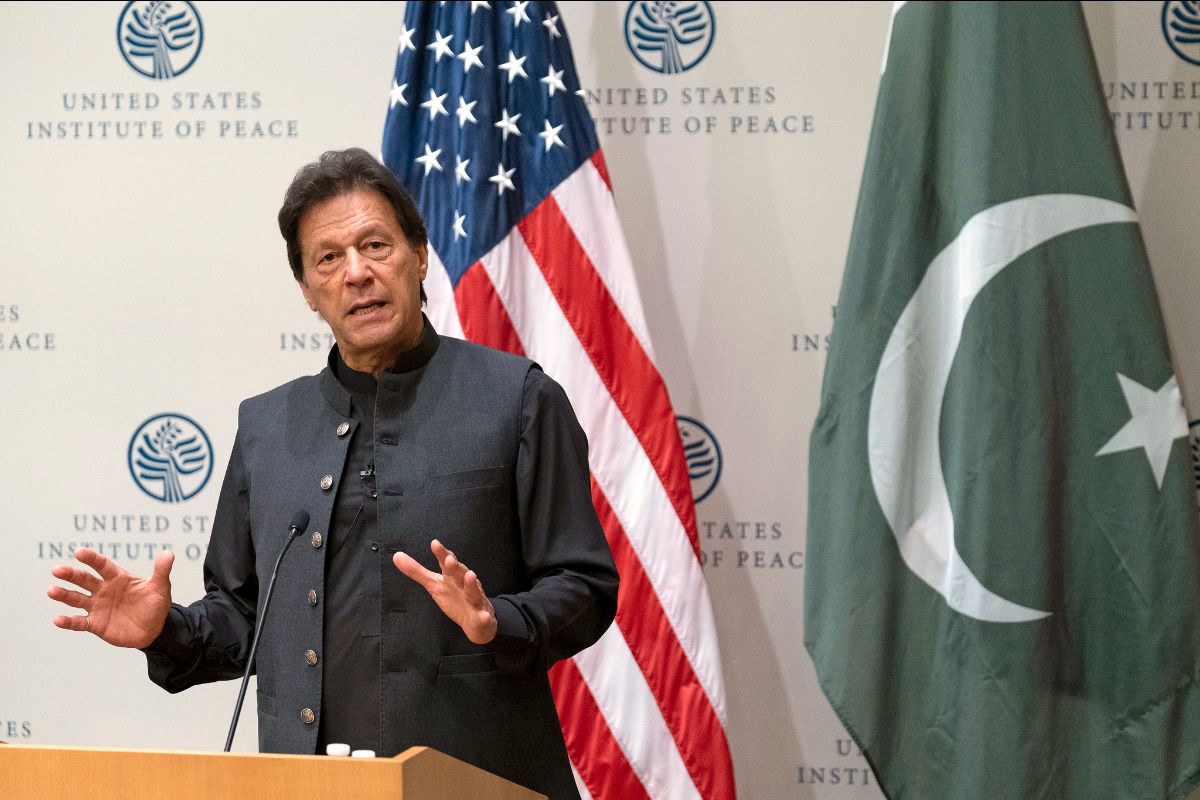 Pakistani Prime Minister Imran Khan stands at a lectern in front of a USA and Pakistan flag.
