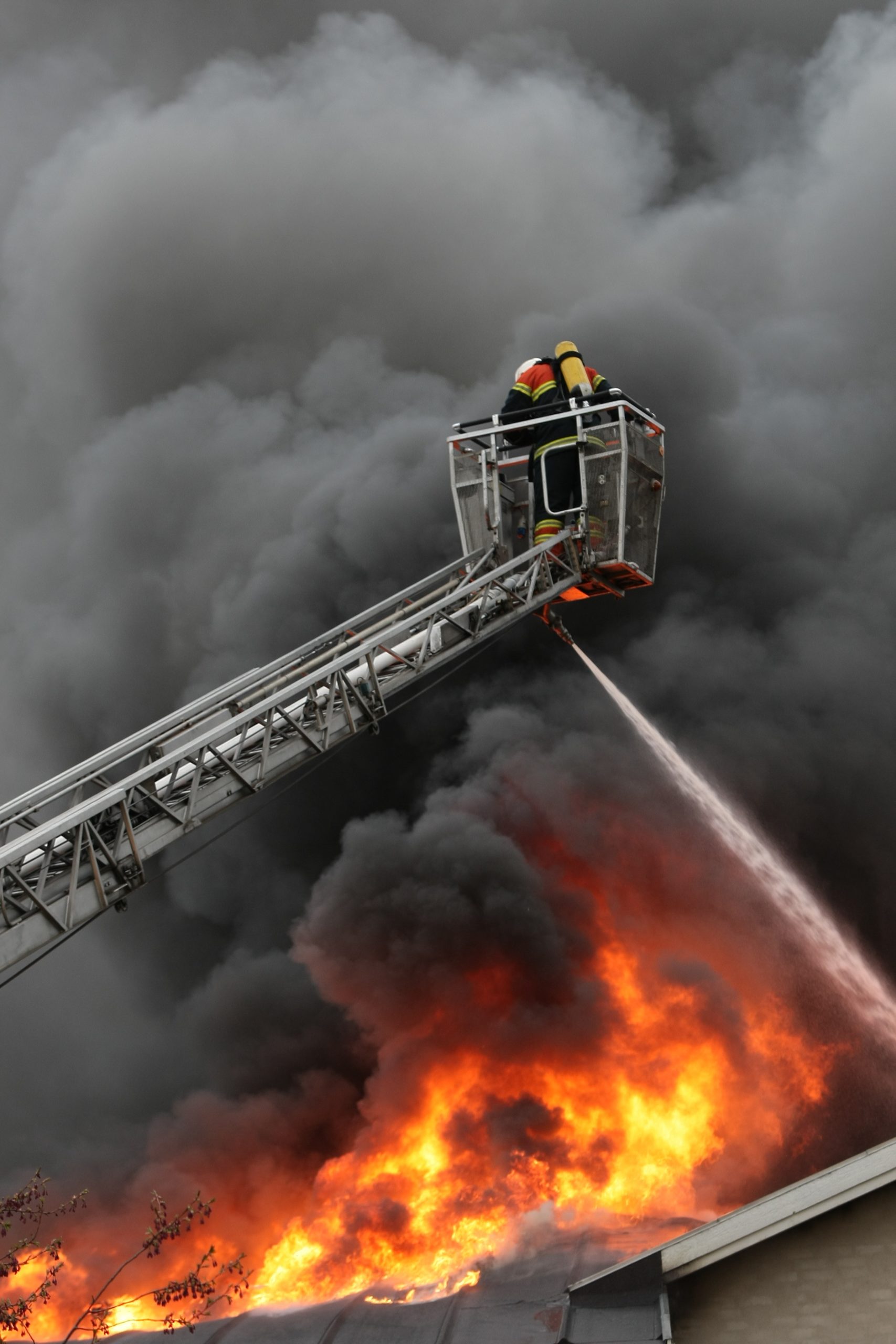 A firefighter on a lift prays water down on a burning roof.