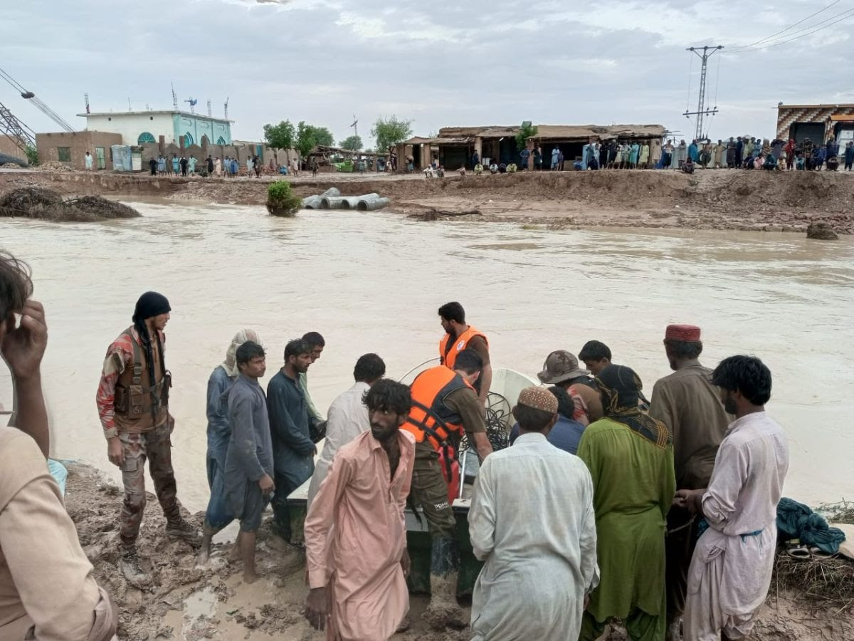 A gathering of several people along a flooded river in Pakistan