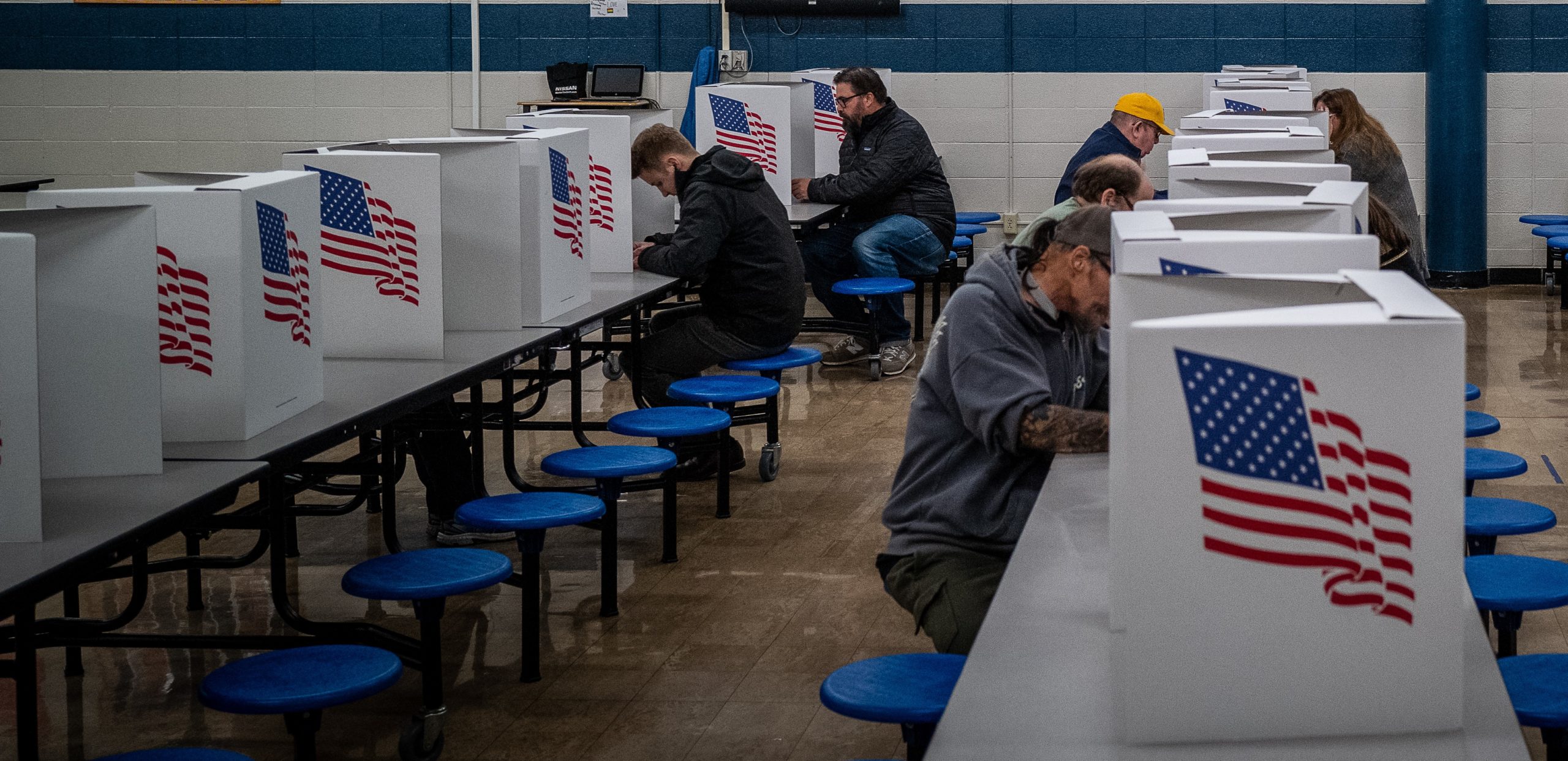 People sit at voting booths at a school.