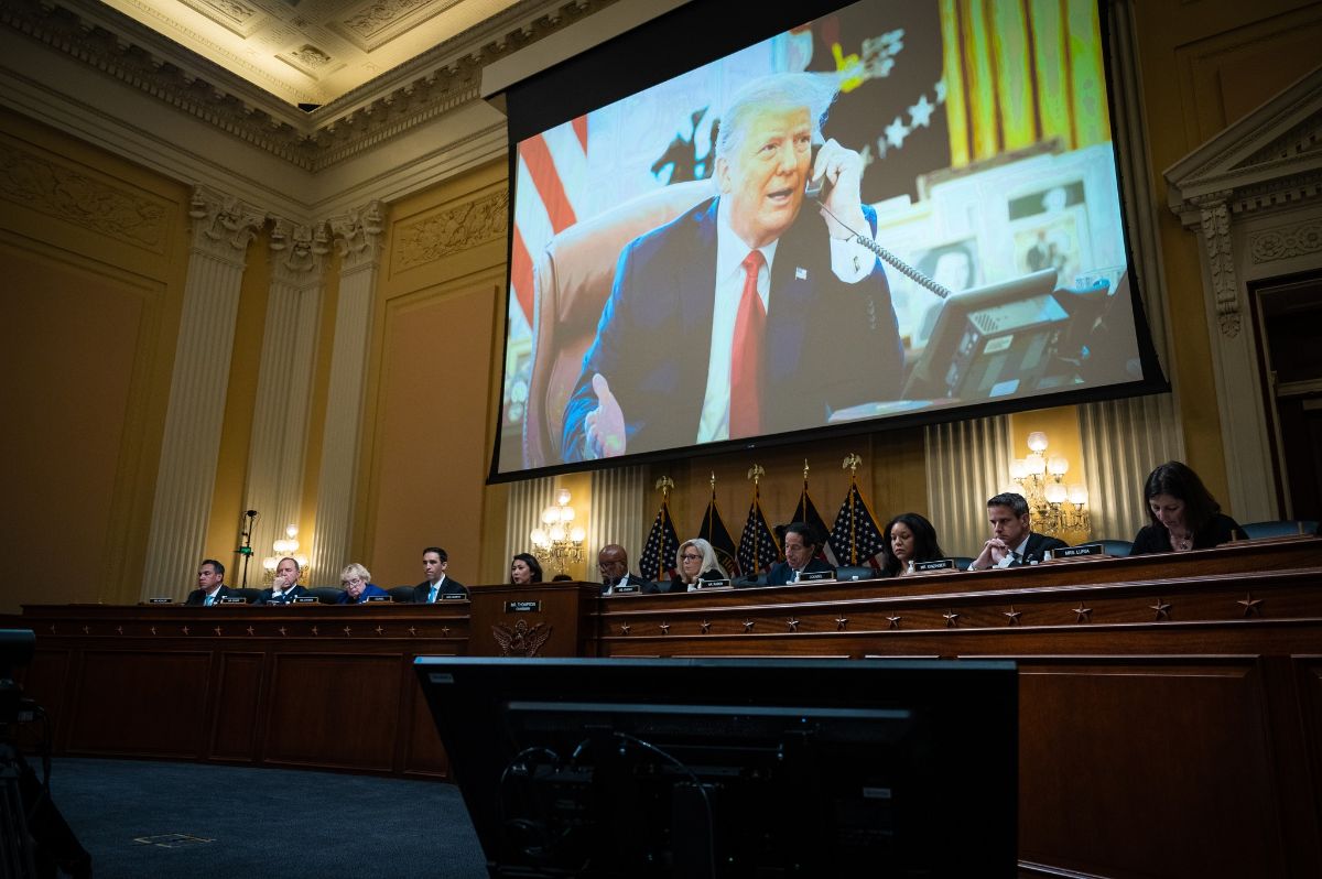 January 6 Committee with a video of former President Trump behind them