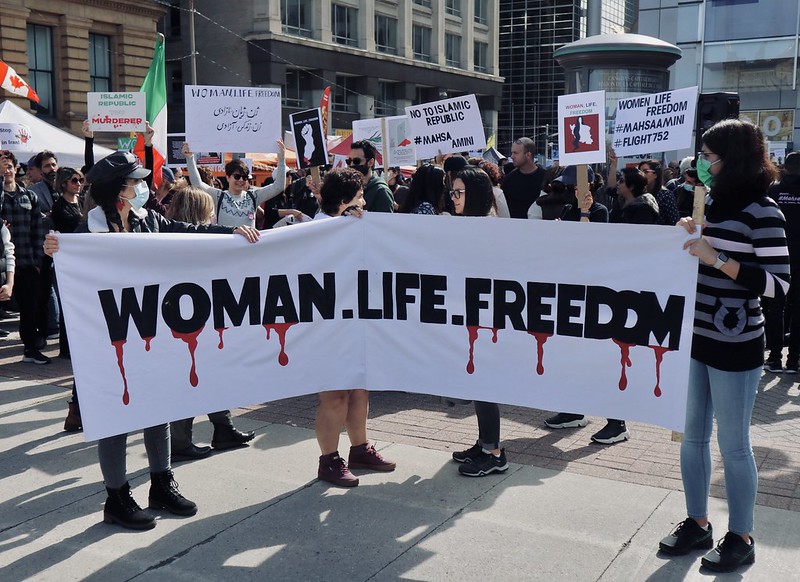People march in support of the protests in Iran. They carry a banner 'Woman.Life.Freedom'