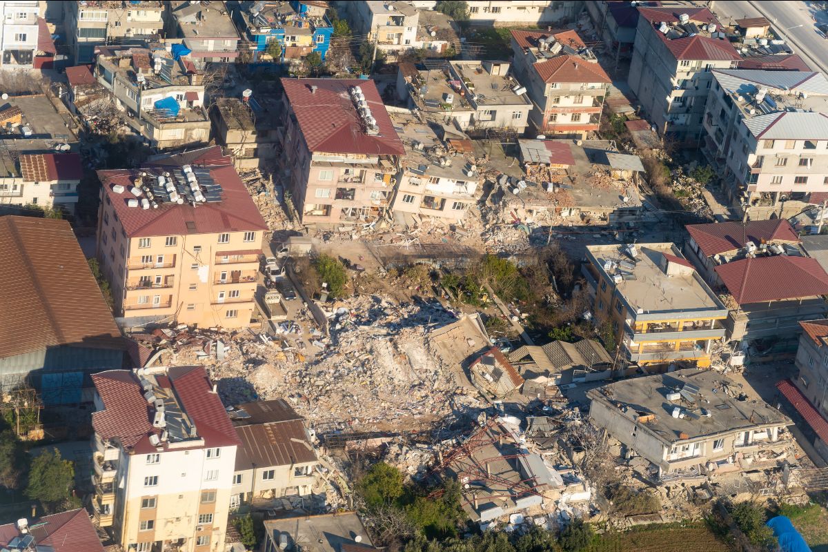 Aerial photo of a neighborhood in Turkey with about 80% of the buildings collapsed. Only two buildings standing appear to have little damage.