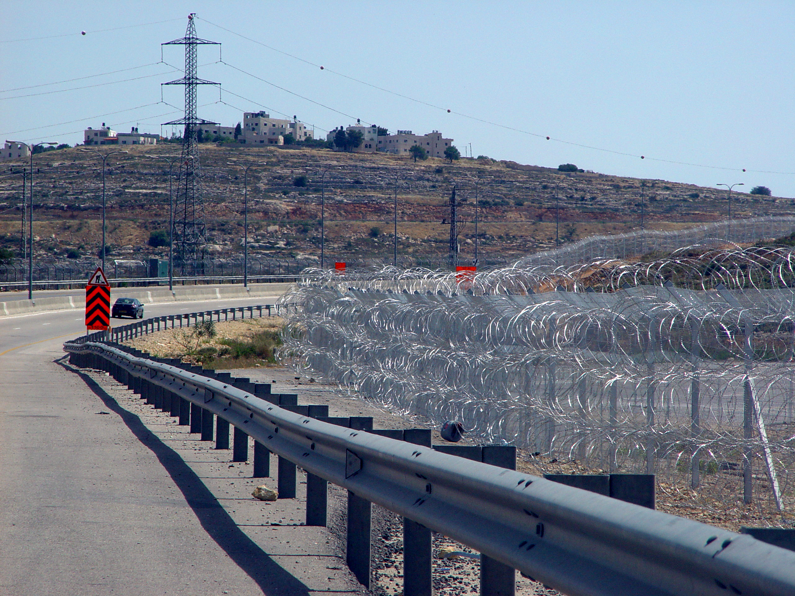 Route 443 near Giv'at Ze'ev Junction, with pyramid-shaped stacks of razor wire forming a section of the Israeli West Bank barrier