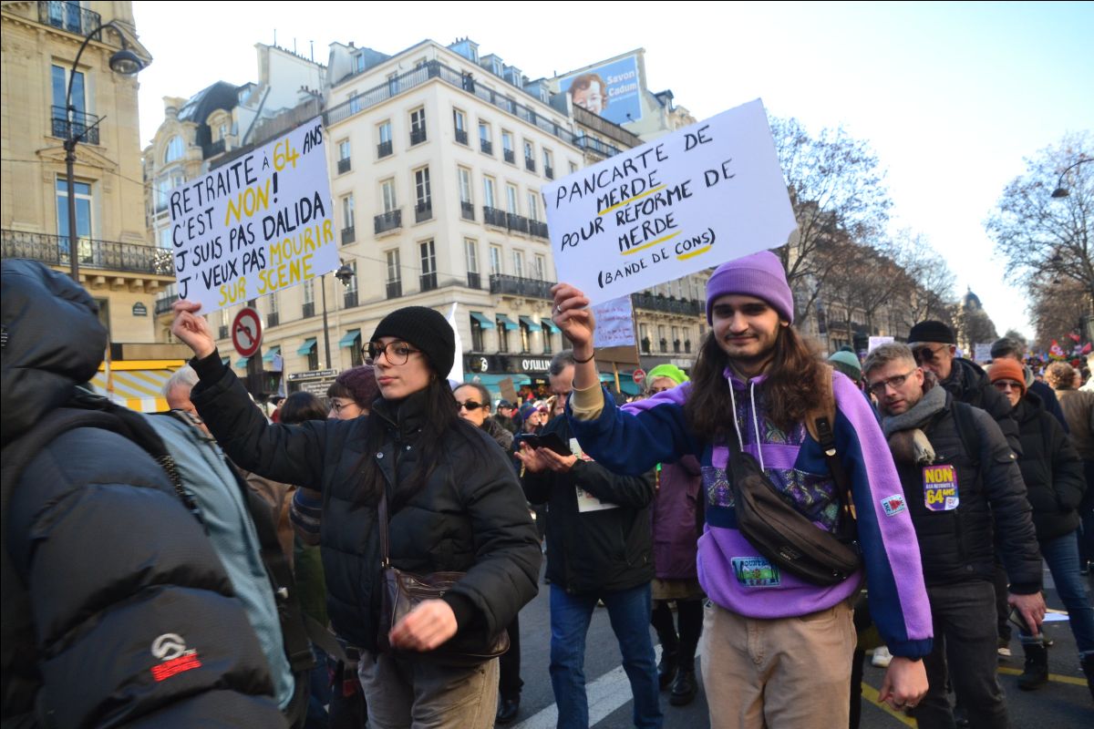 Demonstrators walk through the streets of Paris holding signs.