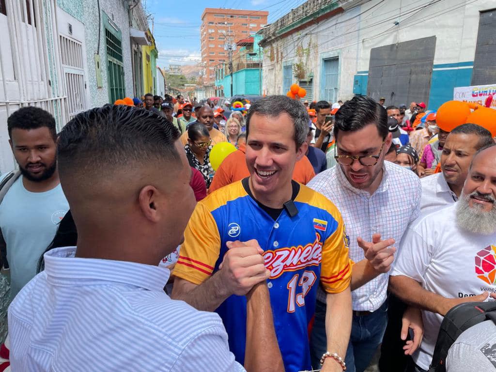 Juan Guaidó out in a crowd of people along a street. He is wearing a Venezuela national baseball team jersey.