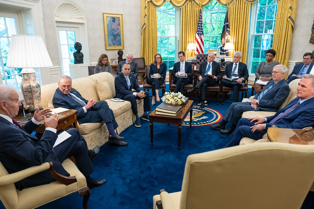 President Joe Biden in a White House room talking to Congressional leadership who sit facing him