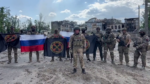 Wagner Group mercenaries stand with flags of Russia and the Wagner group as they claim control of Bakhmut, Ukraine
