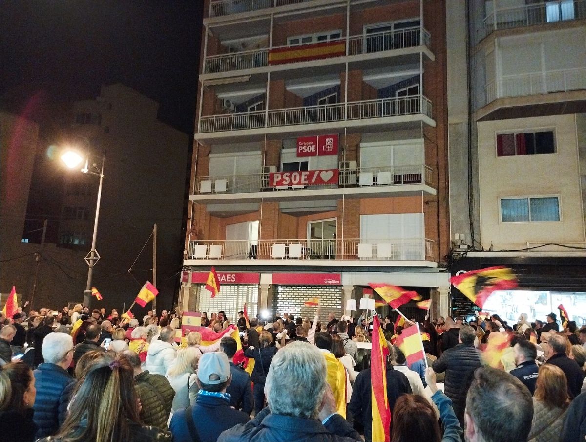 A crowd waves flags in a city street at night. Protesters gathered in Cartagena, Spain, on Nov. 10 to oppose an amnesty law that would pardon Catalan secessionist leaders. 
