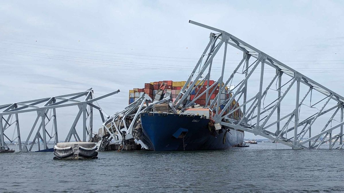 The wreckage from the collapsed remnants of a bridge rest atop a massive container ship