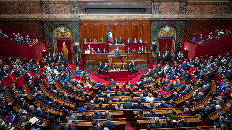 From a high angle the photo looks at the formal French assembly with its tiers of seats and desks. The center includes the leadership of the Assembly.
