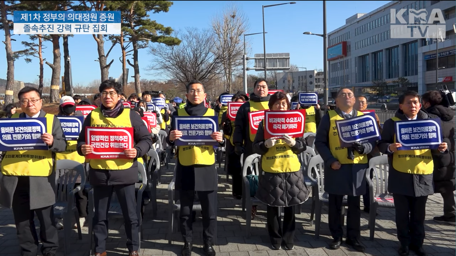 Group of people wearing yellow vests holding protest signs in Korean.