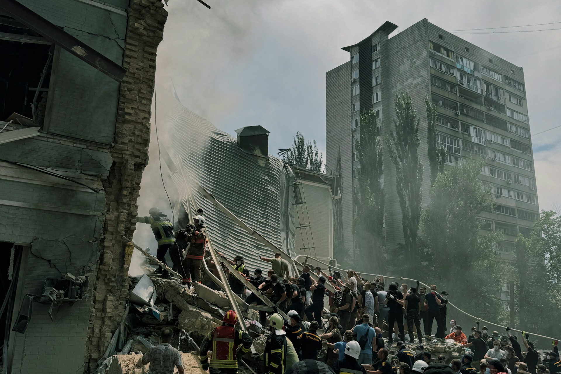 Rescue operations at a collapsed building with emergency responders and civilians among the rubble.