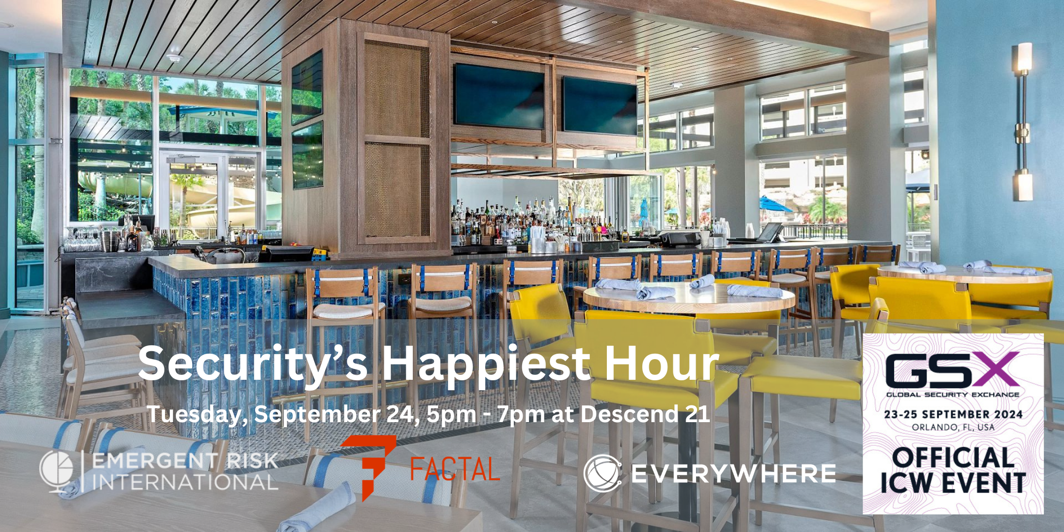 The image is an interior view of a modern bar named Descend 21. The bar encompasses a sleek and stylish design with a polished gray counter featuring blue-tiled accents. Various bottles of alcohol are displayed behind the counter. The bar is surrounded by high wooden bar stools with blue cushioning. In the foreground, there are round tables with chairs, some in yellow and others in natural wood. Each table is set with a rolled-up napkin. The setting is bright due to the large windows allowing natural light to pour in, providing a view of lush greenery outside.