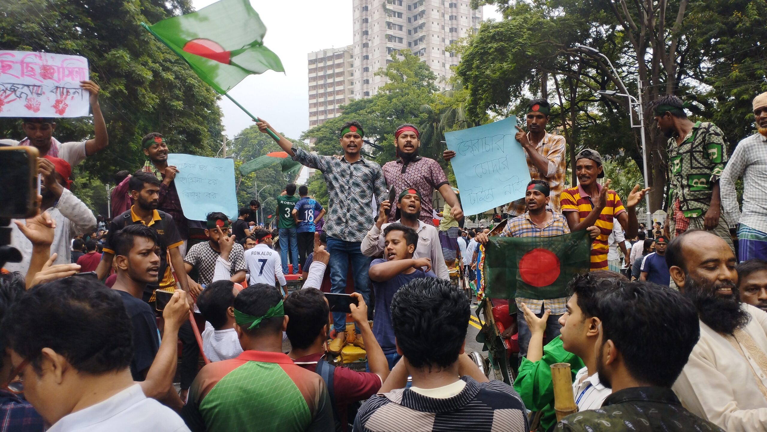 Crowd of people at a rally, some holding signs and a flag.