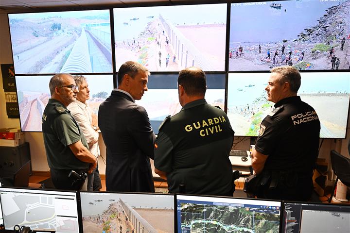 Photo off five men looking at many TV monitors assessing migrant influx by sea and land.